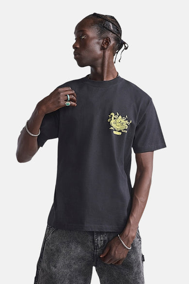T-shirt noir à manches courtes de VANS "OFF THE WALL", avec une impression graphique sur la poitrine, porté avec des jeans gris.