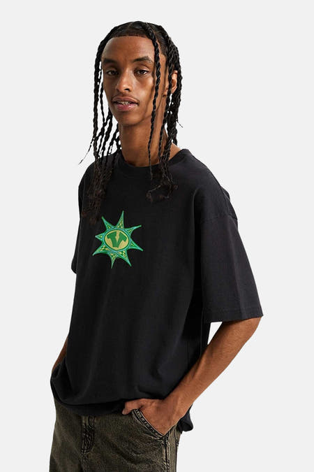 T-shirt noir à manches courtes de VANS "OFF THE WALL", avec une impression graphique verte sur la poitrine.