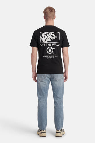T-shirt noir VANS "OFF THE WALL" avec logo de marque blanc et imprimé texte dans le dos, porté avec un jean bleu et des baskets.