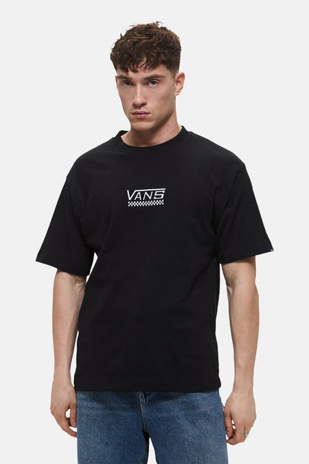 T-shirt noir à manches courtes de VANS, avec un logo blanc et un motif damier sur la poitrine, porté avec un jean bleu.
