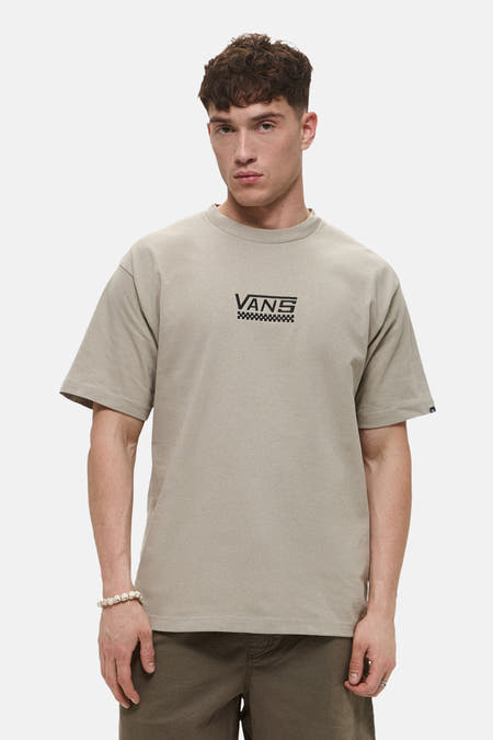 T-shirt beige à manches courtes de Vans, avec logo sur la poitrine et porté avec un bracelet en perles.