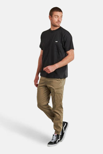 T-shirt noir à manches courtes de VANS, porté avec un pantalon kaki et des baskets noires et blanches.