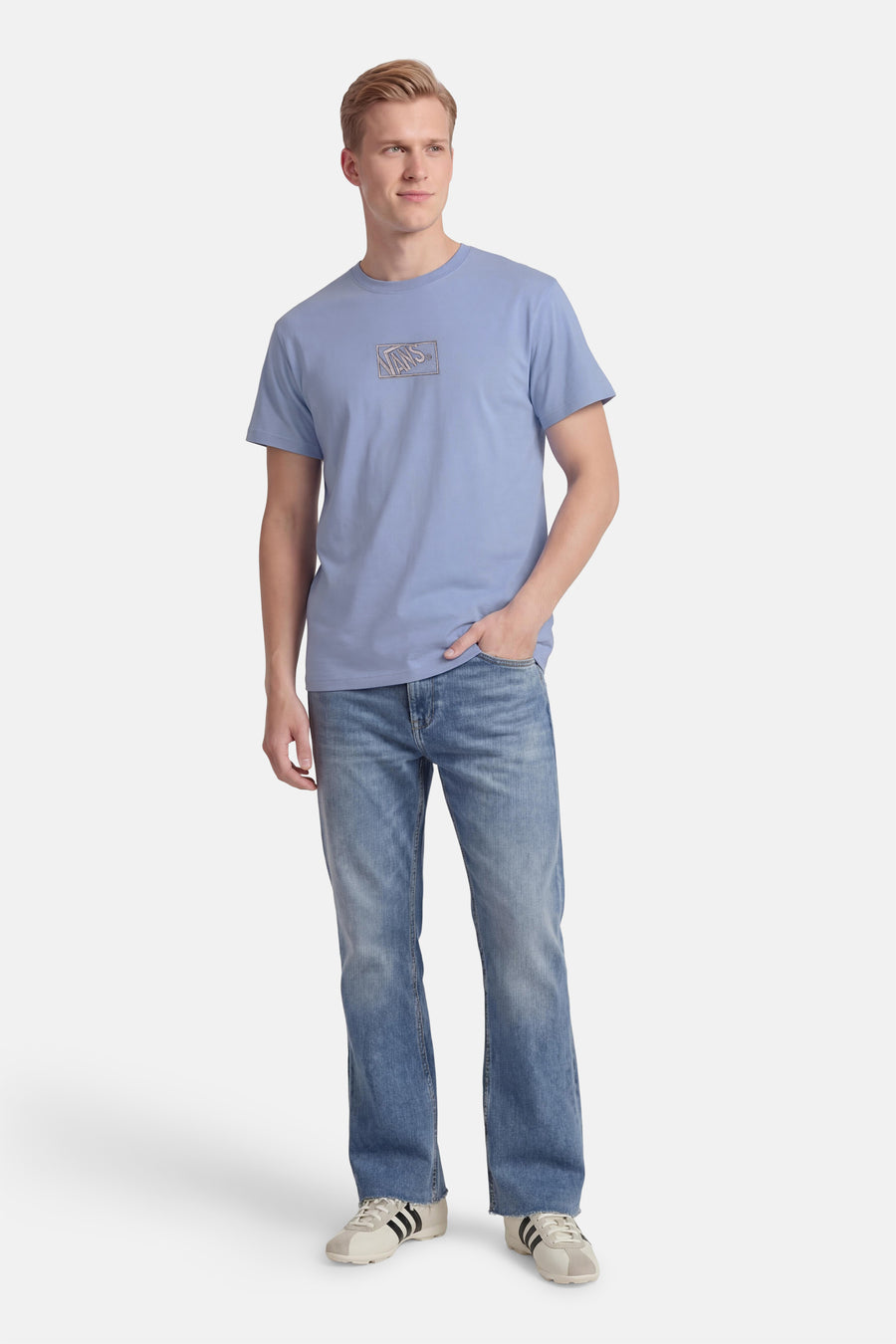 T-shirt bleu VANS "OFF THE WALL", à manches courtes et logo sur la poitrine, porté avec un jean.