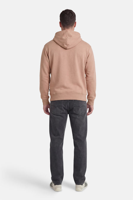 Pull beige à capuche VANS "OFF THE WALL", vu de dos, porté avec un jean gris foncé et des baskets.