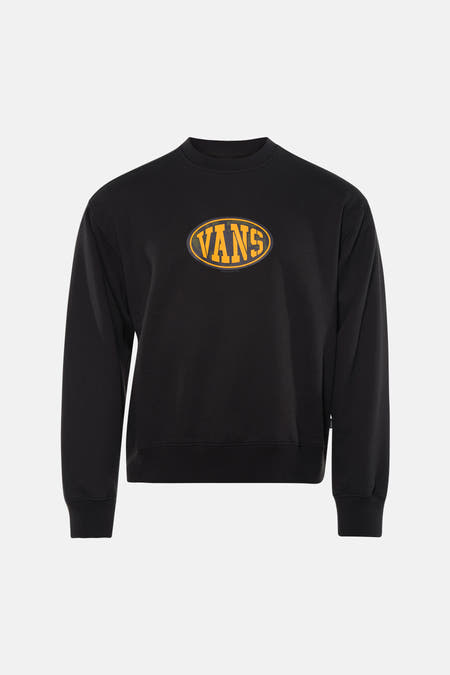 Pull noir VANS "OFF THE WALL" avec logo jaune sur la poitrine, associé à un jean bleu et des baskets blanches.