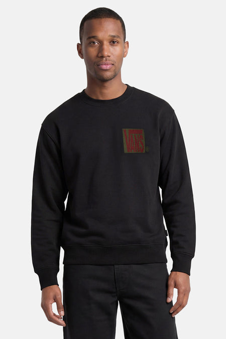 Zwarte sweater van VANS “OFF THE WALL” met ronde hals en rood 'VANS' logo op een olijfgroene rechthoek op de borst.