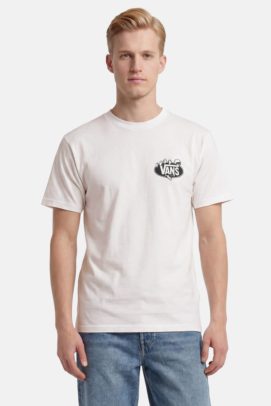 T-shirt blanc Vans avec logo ovale noir de mains squelettiques sur la poitrine, porté par un homme en jean.