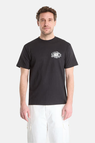 T-shirt noir de VANS avec logo stylisé blanc sur la poitrine gauche, porté par un homme en pantalon blanc.