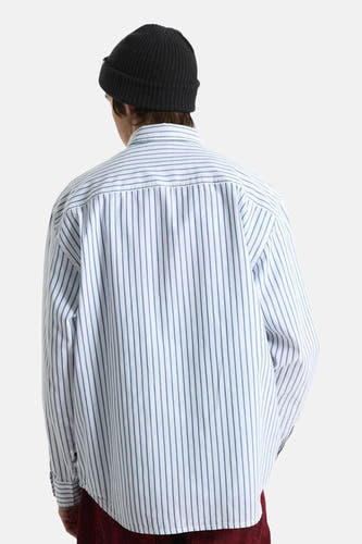 Wit gestreept hemd van VANS “OFF THE WALL”, gedragen door een persoon van achteren, met een zwarte muts en bordeauxrode broek.