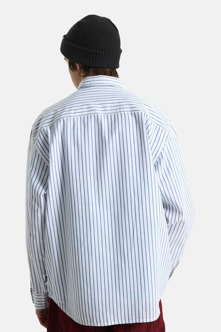 Wit gestreept hemd van VANS “OFF THE WALL”, gedragen door een persoon van achteren, met een zwarte muts en bordeauxrode broek.