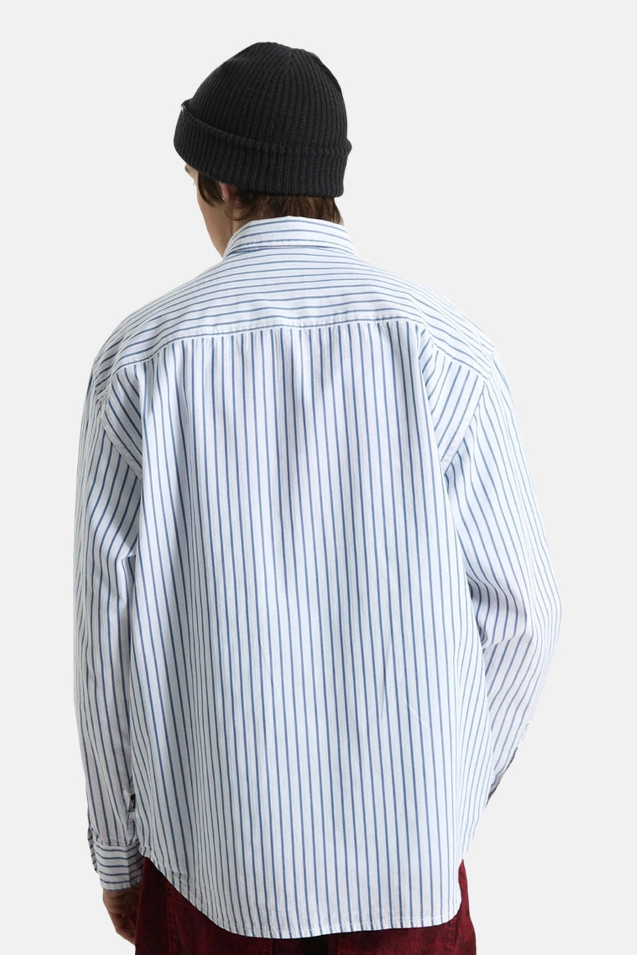 Wit gestreept hemd van VANS “OFF THE WALL”, gedragen door een persoon van achteren, met een zwarte muts en bordeauxrode broek.