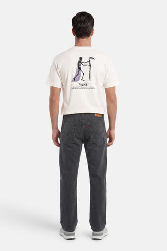 T-shirt écru VANS "OFF THE WALL" avec imprimé squelette et texte dans le dos, porté par un homme en jean côtelé et baskets.