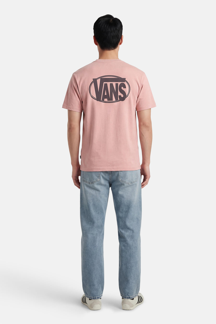 T-shirt rose VANS "OFF THE WALL" avec un grand logo dans le dos, porté avec un jean bleu et des baskets blanches.