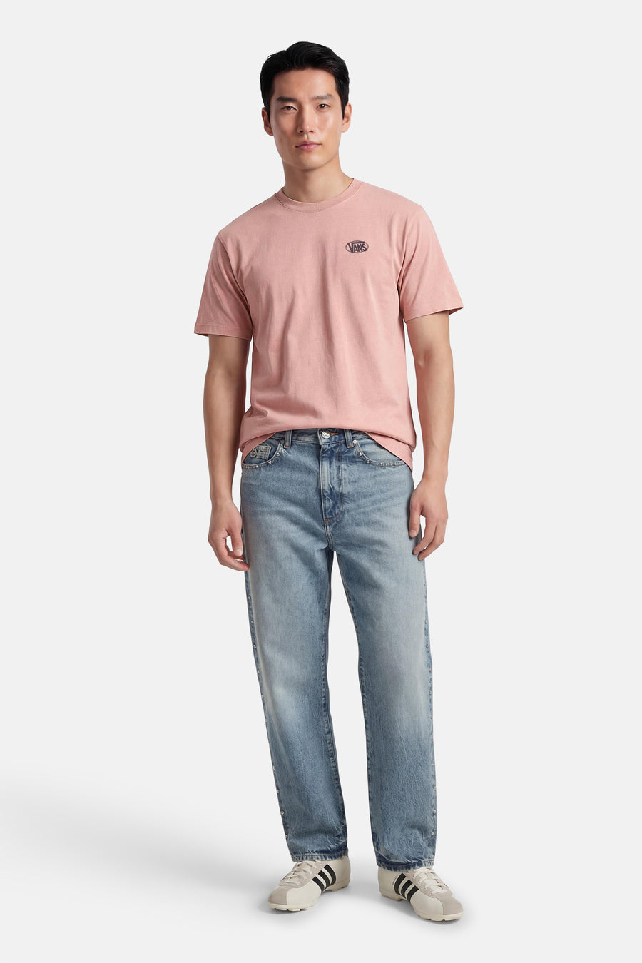 T-shirt rose VANS "OFF THE WALL", à manches courtes, porté avec un jean et des chaussures de couleur crème.