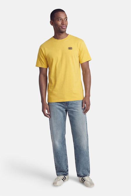 T-shirt jaune VANS "OFF THE WALL", porté avec un jean et des baskets crème à rayures noires.