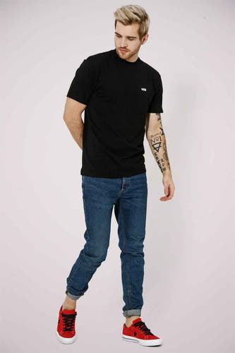 T-shirt noir de Vans, porté avec des jeans et des baskets rouges.