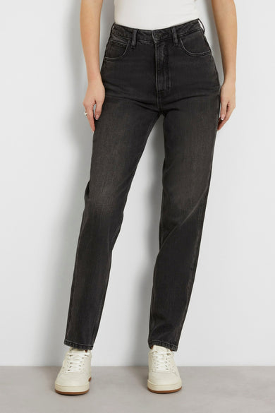 Jean mom gris Guess, avec logo de marque sur la poche arrière et baskets blanches.