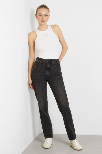 Jean mom gris de Guess, avec une taille haute et des jambes droites, associé à un chemisier blanc et des baskets crème.