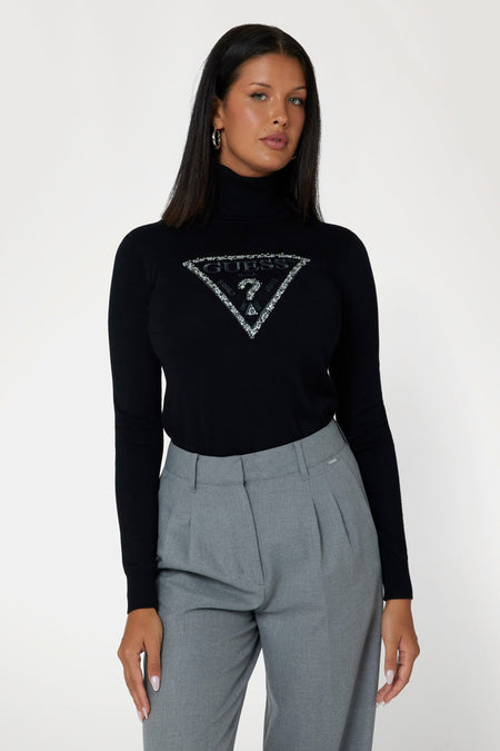 Pull noir à col roulé de Guess®, à manches longues, porté par un mannequin en pantalon gris, vue de côté.