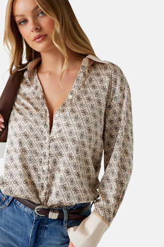 Een vrouw draagt een beige blouse met een bruin patroon, blauwe jeans en een bruine riem.