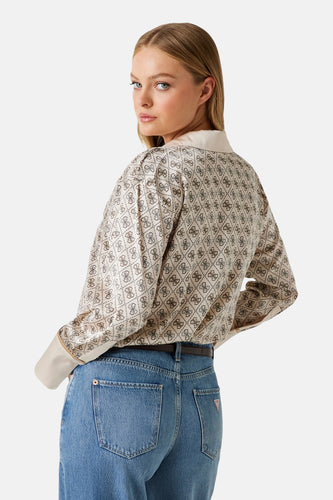 Vrouw draagt beige blouse met patroon en blauwe jeans.