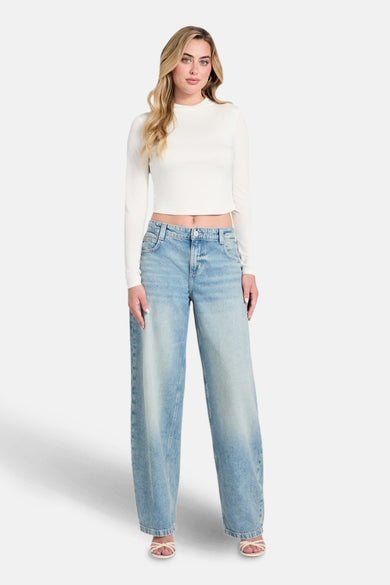 Jean en denim bleu clair spécial fit de Guess, avec des jambes larges et porté avec un haut blanc.
