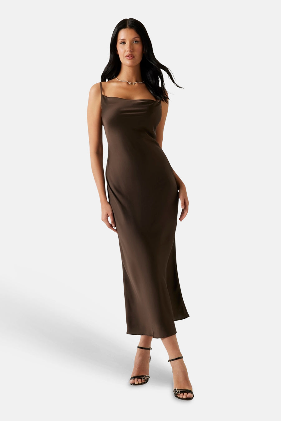 Robe sans manches marron Guess avec encolure drapée et aspect satiné, portée par un mannequin avec des sandales noires.