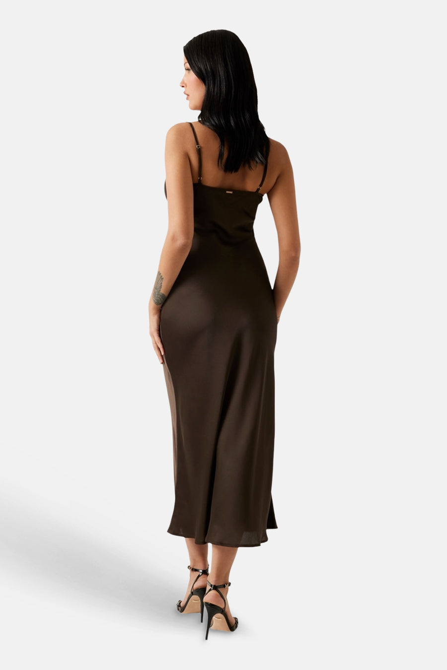 Robe nuisette en satin marron de Guess, avec fines bretelles, vue de dos, portée avec des talons noirs.