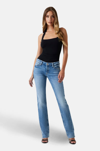 Jean droit en denim bleu clair de Guess, porté avec un haut noir et des sandales à brides.
