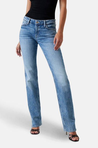 Jean droit en denim bleu clair de Guess, avec une légère usure et stylé avec des sandales noires.