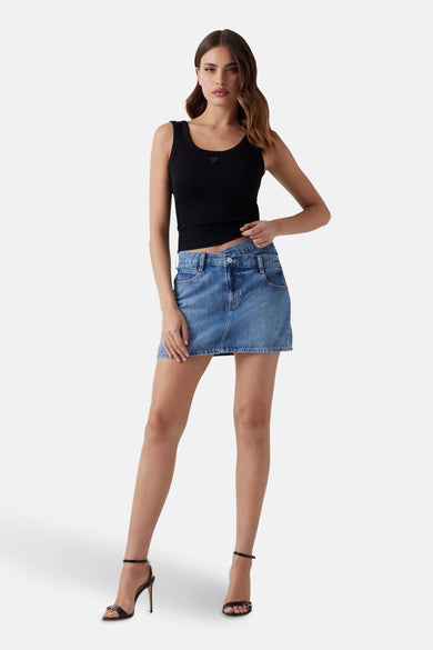Robe courte bleue de Guess, avec texture denim, associée à une chemise noire et des talons.