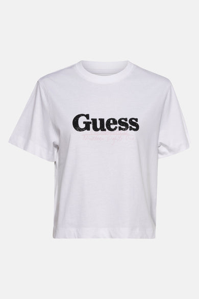 T-shirt blanc à manches courtes de Guess avec imprimé logo noir et un texte rose en dessous.
