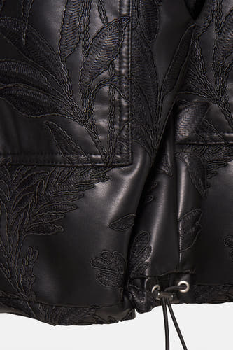 Gilet chauffeuse noir de Guess, avec un motif de feuille complexe et un détail de cordon à la taille.