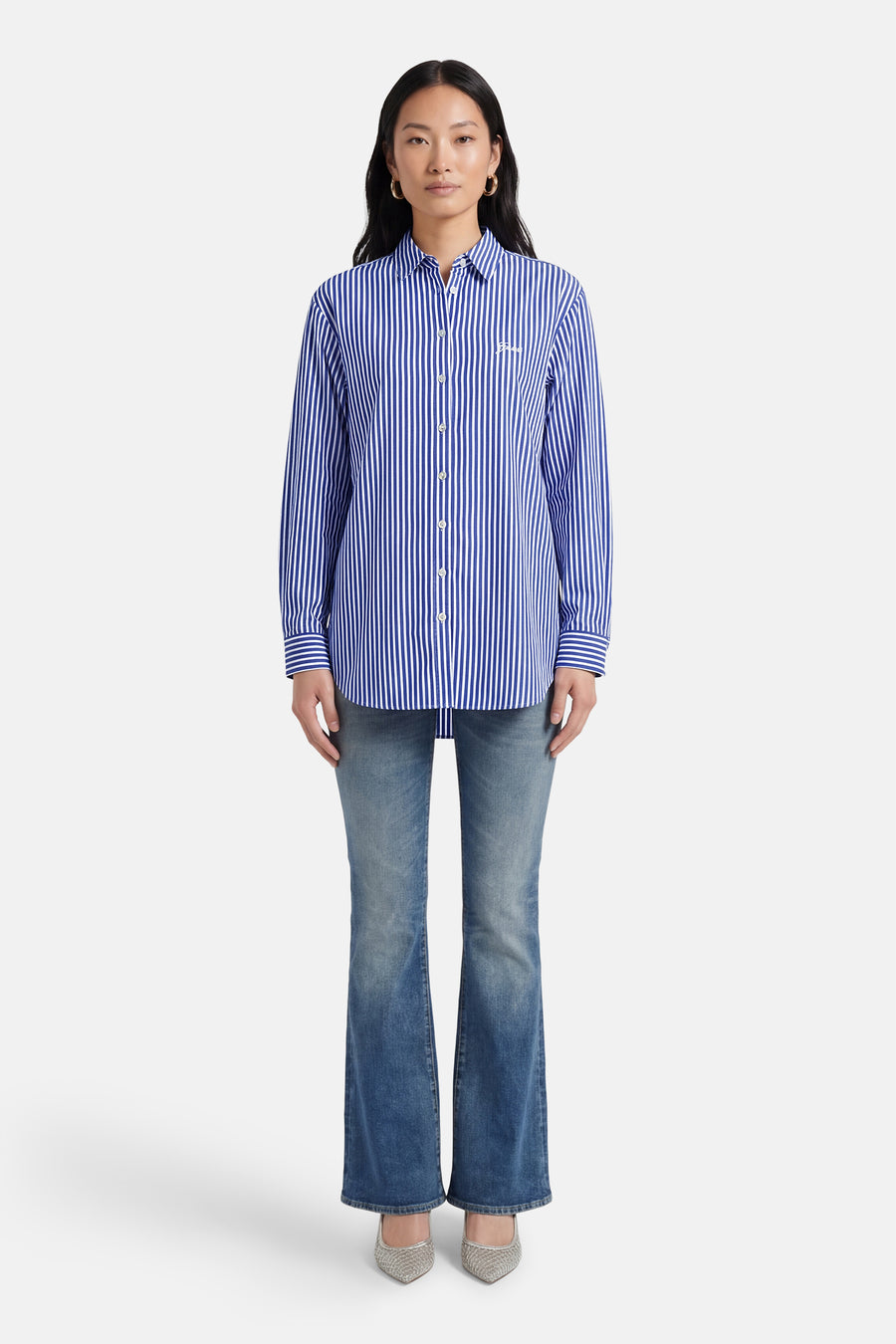 Chemise bleue rayée à manches longues de Guess, portée avec un jean et des chaussures argentées.