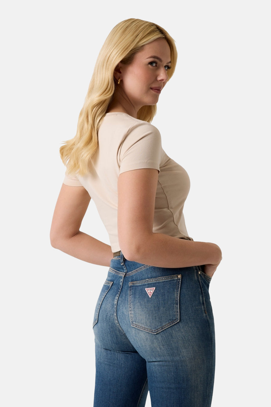 Beige T-shirt met korte mouwen van Guess, strak model met korte snit, gedragen met blauwe jeans, zijaanzicht.