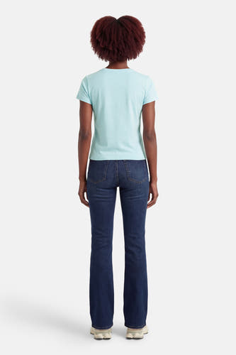 T-shirt bleu à manches courtes de Guess®, vu de dos, associé à un jean bleu foncé et des baskets blanches.