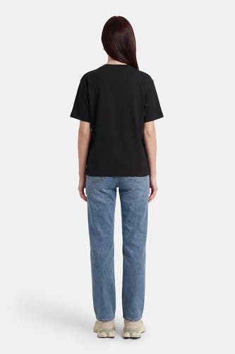 T-shirt noir à manches courtes de Guess, dos, combiné avec un jean bleu et des baskets beiges.