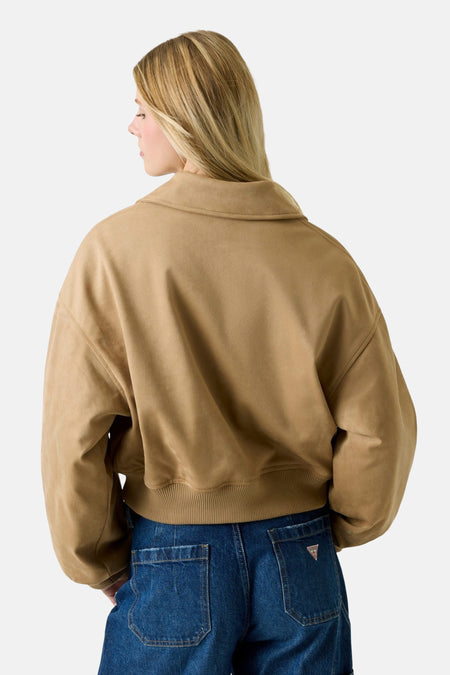 Achterkant van een vrouw in een bruine jas en blauwe jeans.