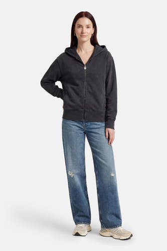 Gilet gris de Guess, à manches longues et fermeture éclair, porté avec un jean et des baskets.