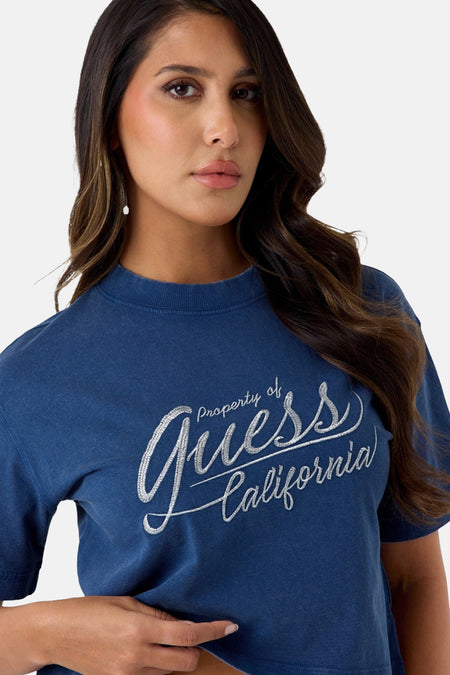 Blauwe korte mouwen t-shirt van Guess met zilveren glitterlogo en ronde hals, gedragen door model in lifestyle shot
