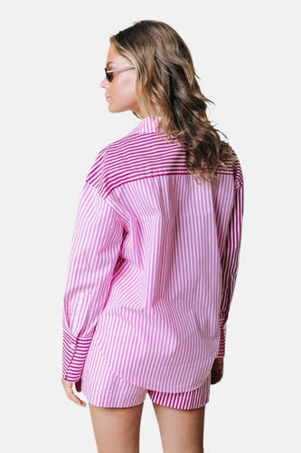 Chemisier rose à manches longues de COLOURFUL REBEL, avec des rayures verticales et horizontales roses au dos, porté de dos par un mannequin avec des lunettes de soleil.