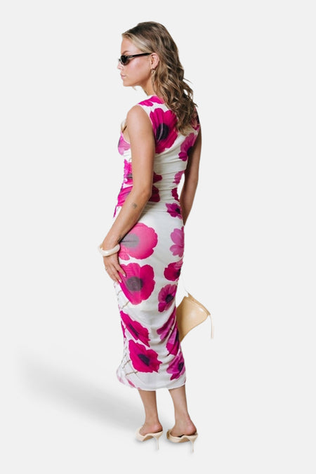 Wit mouwloos kleedje met roze bloemenprint van COLOURFUL REBEL, een aansluitend midi-model met ruches, getoond van de zijkant.