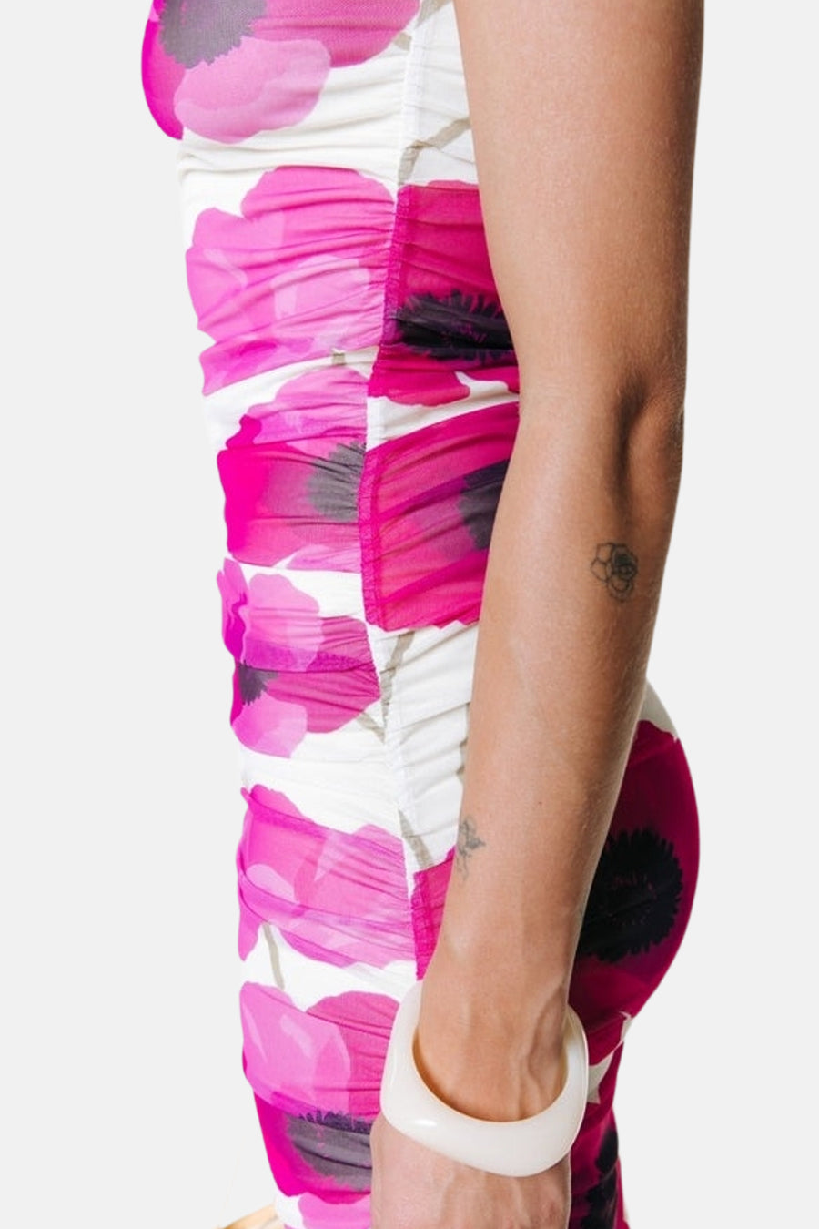 Multicolor mouwloos kleedje van COLOURFUL REBEL met roze papaverprint en geplooide zijden, in zijprofiel gedragen met witte armband.
