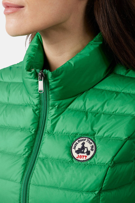 Gilet vert de JOTT, avec une texture matelassée et un badge de marque rond sur la poitrine.