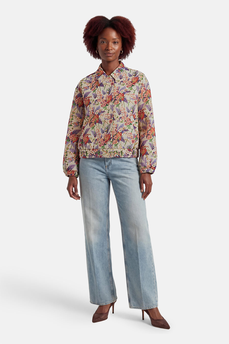 Veste courte multicolore de COLOURFUL REBEL, à motif floral, portée avec un jean bleu et des talons marron.
