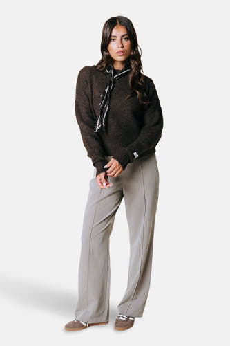 Pull marron avec col rond de COLOURFUL REBEL, associé à un foulard décoratif autour du cou, combiné à des pantalons rayés et des baskets.