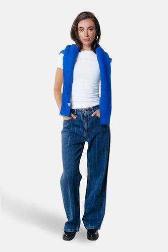 Jean bleu marine, large de COLOURFUL REBEL, avec des rayures verticales, associé à une chemise à carreaux et un chapeau imprimé d'animaux.
