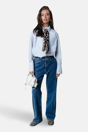 Donkerblauwe, wijde jeans van COLOURFUL REBEL, met verticale strepen, gecombineerd met een gestreept overhemd en een dierenprint sjaaltje.
