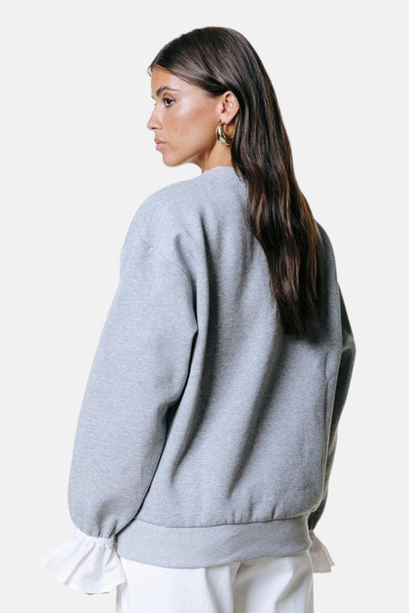 Pull gris de COLOURFUL REBEL, vu de dos, avec des manches longues et des boucles d'oreilles dorées.