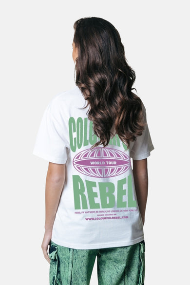 Achterkant van een vrouw met een wit T-shirt met groene en paarse opdruk en groene broek.